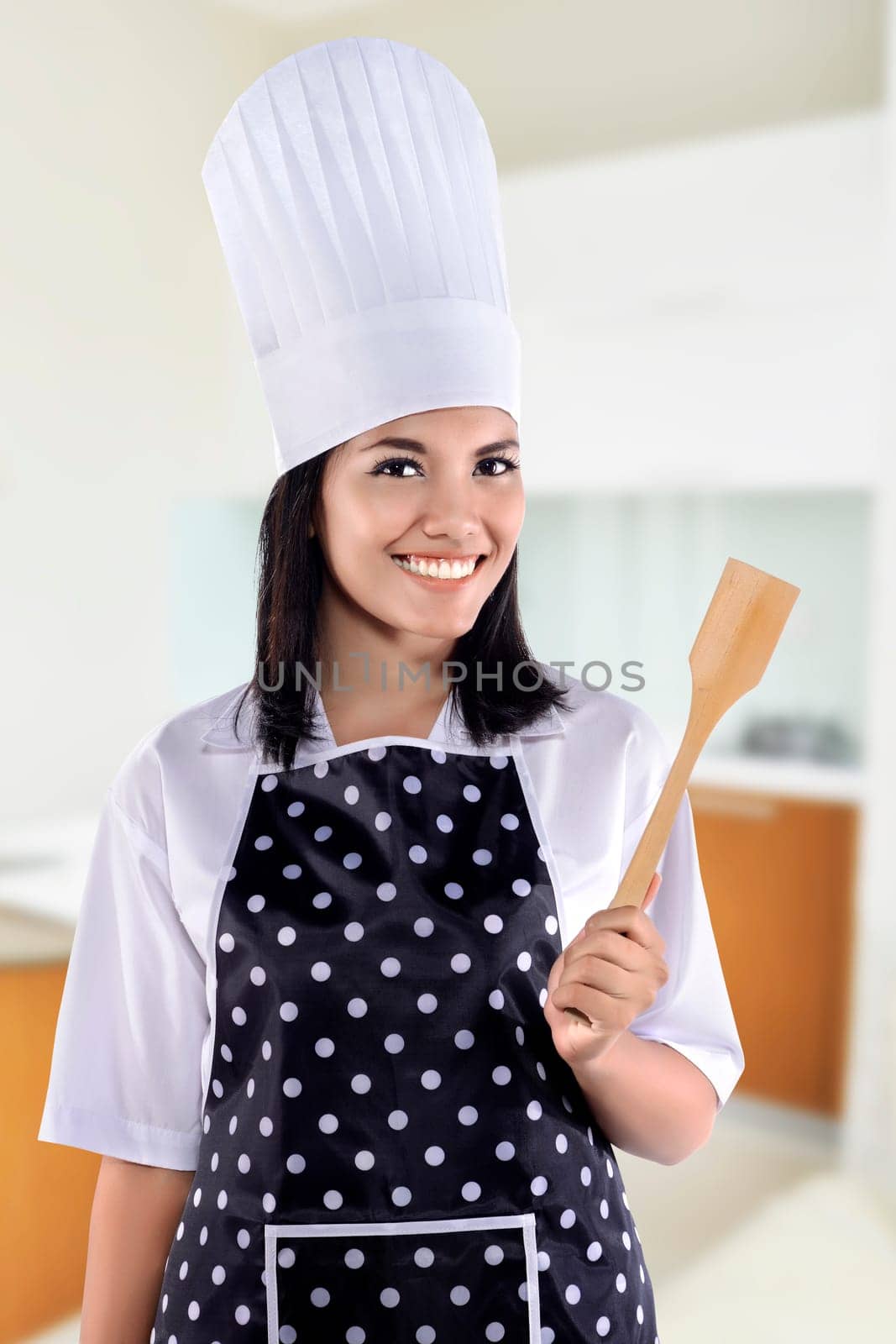 Portrait of young woman chef over kitchen background