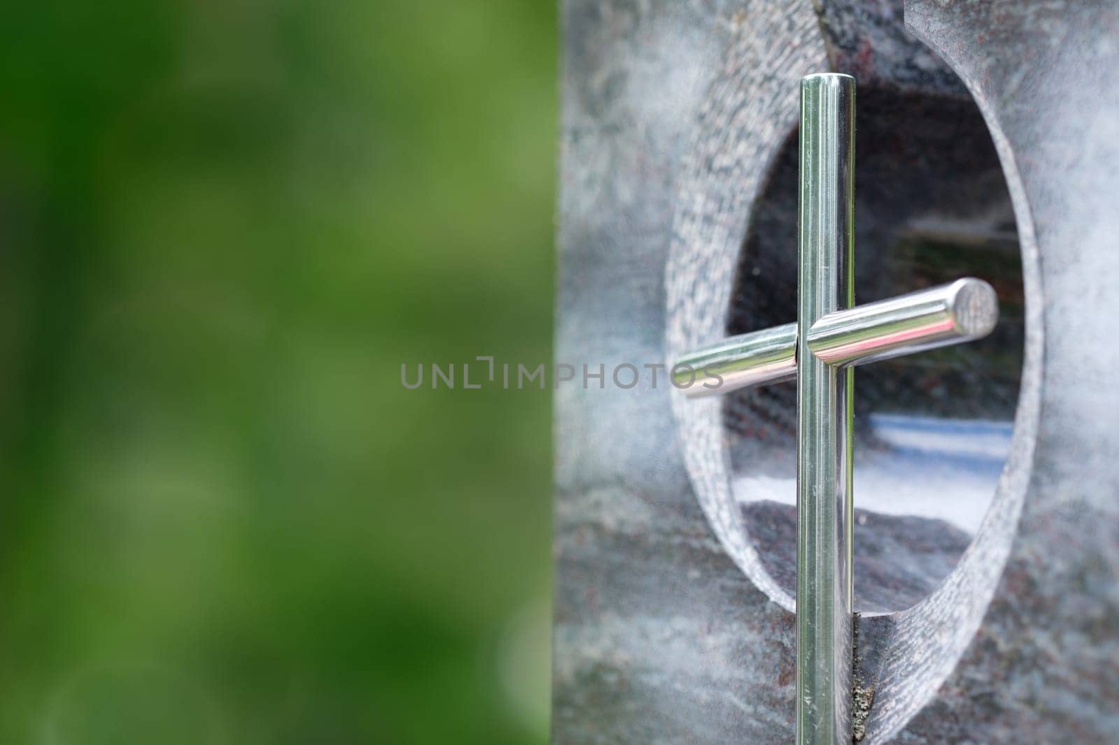 Crucifix on a tombstone with a green blurred background