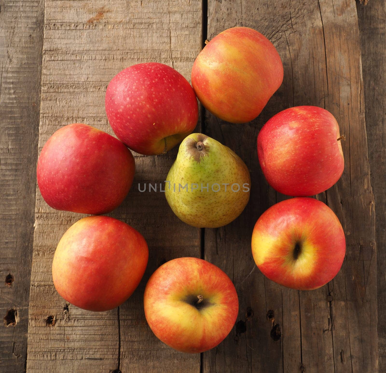 Red apples and green pear on a rustic wooden table