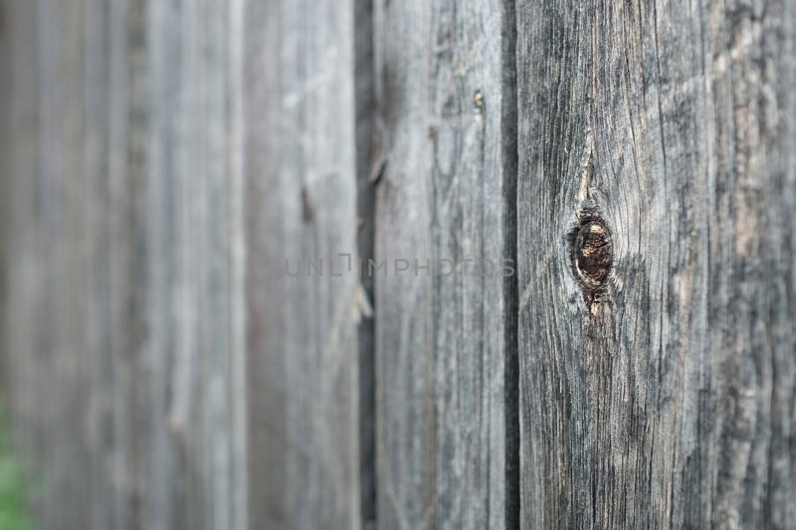 Grey wall made of wood and board with knothole and blur in the background