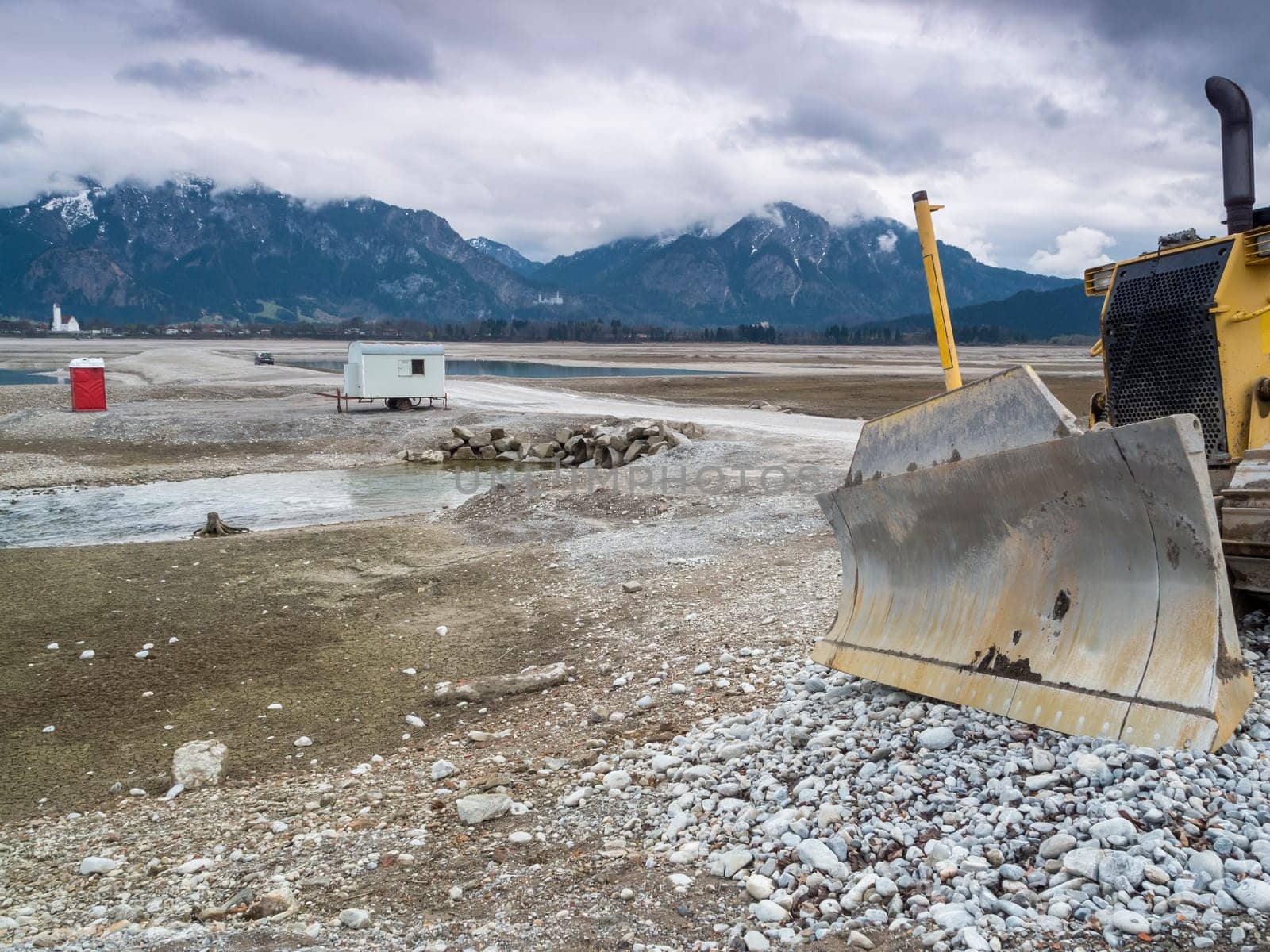 Shield of a bulldozer in the drained Forggensee near Füssen / Bavaria. The Forggensee is fed by thawing snow from the high Alps and is a reservoir for sedimentary rocks. In spring,the lake is emptied to remove the sedimentary rock. In summer,the lake has returned to its normal water level and is navigated by excursion boats.