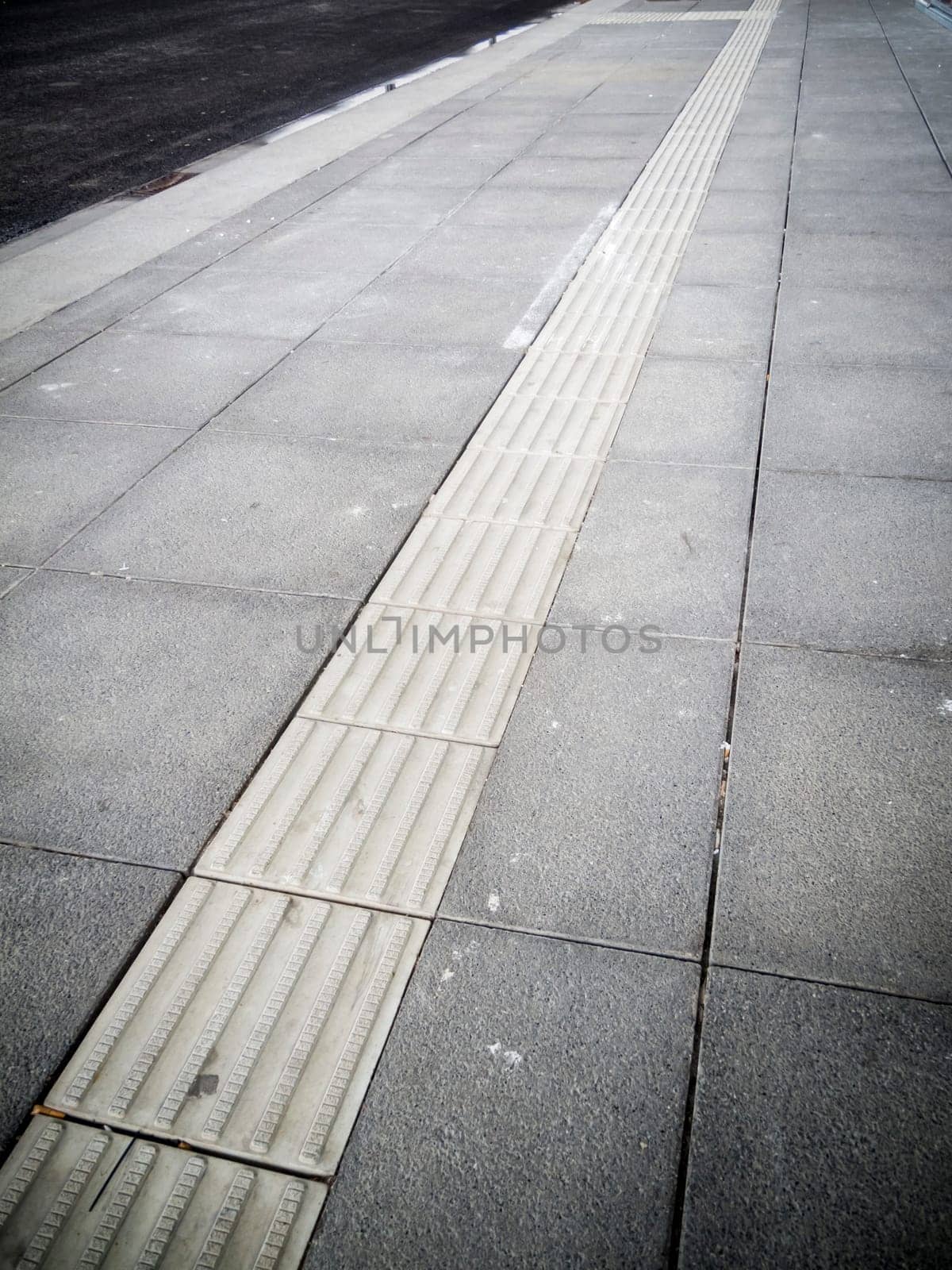Sidewalk with pavement slabs and white dividing line.