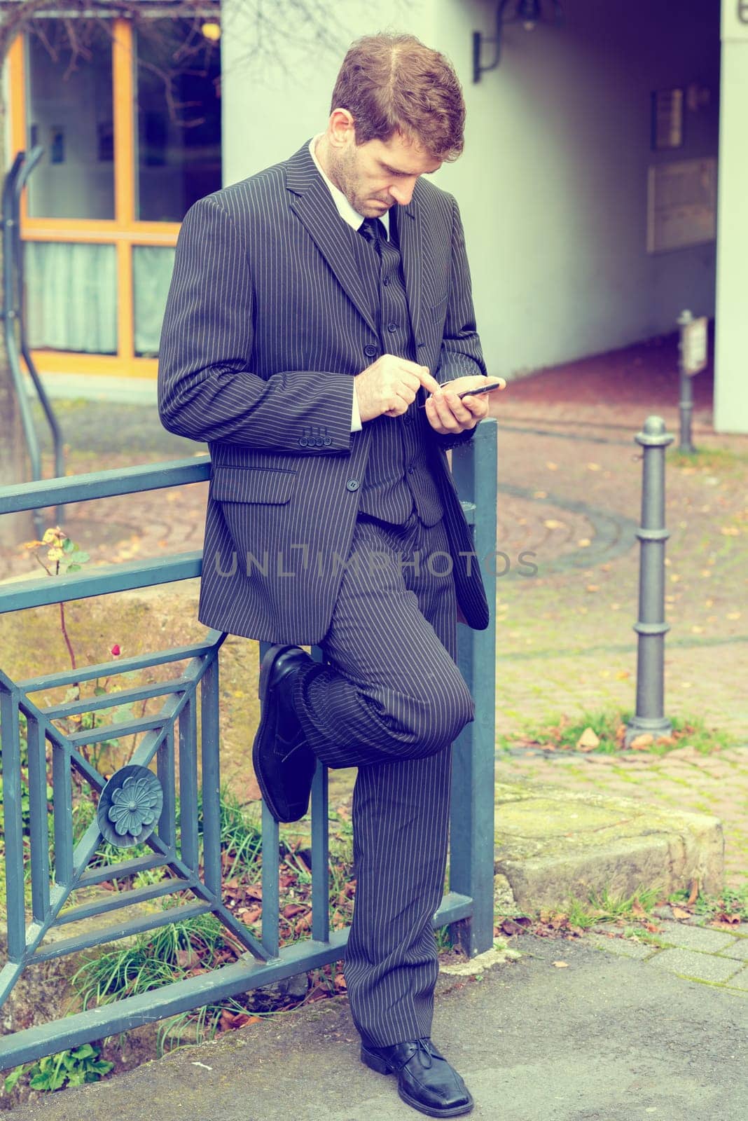 businessman in suit in front of city- background with smartphone