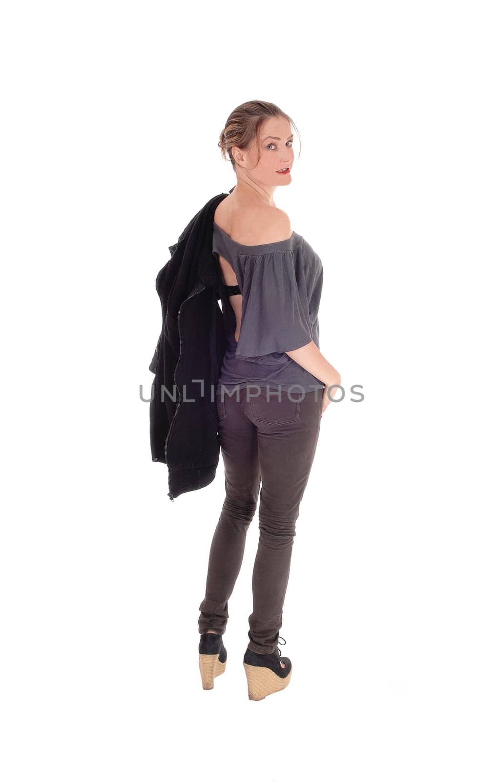 A slim young woman in jeans with her jacket over her shoulder is.ready for a walk, isolated for white background..