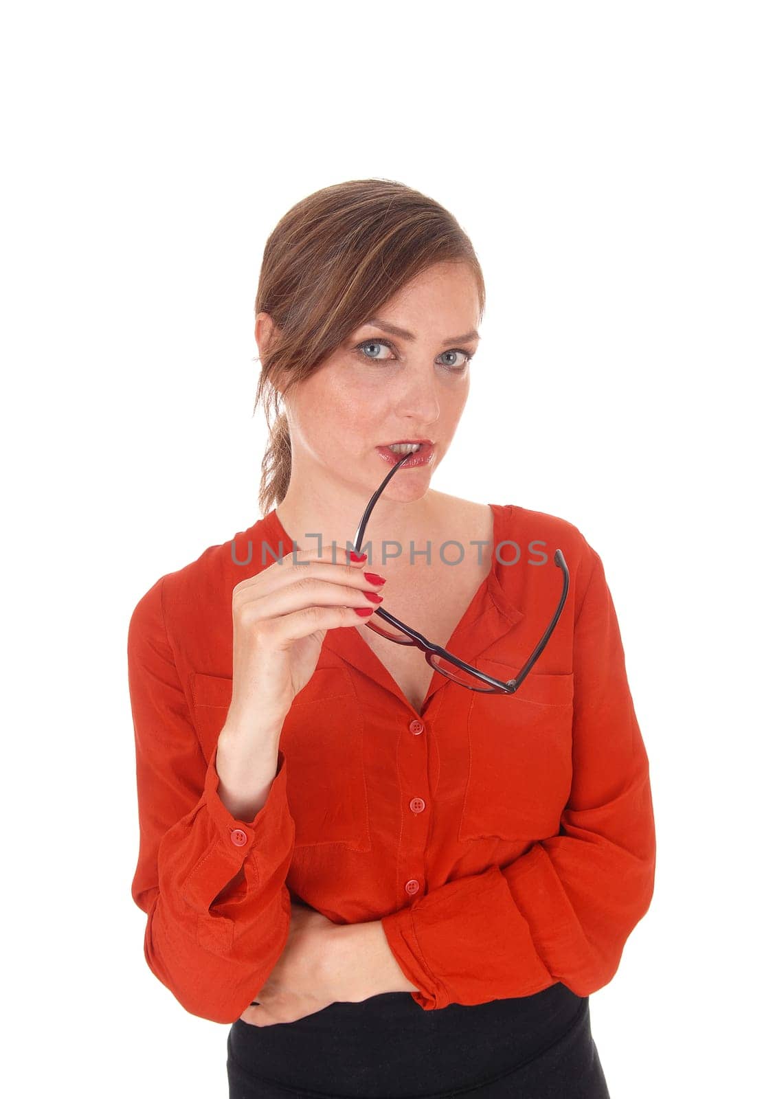 A beautiful young businesswoman standing in a red blouse with her.glasses in her mouth, thinking hard, isolated for white background..