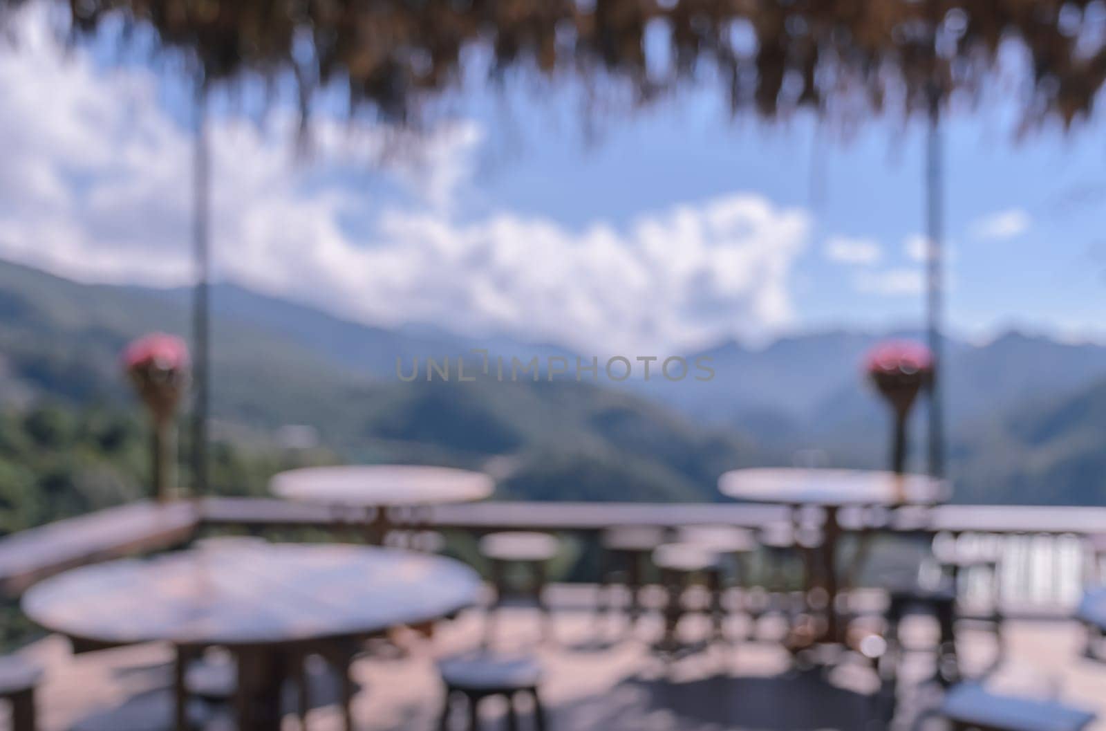 Blurred image of outdoor terrace cafe and restaurant tables with mountain view background