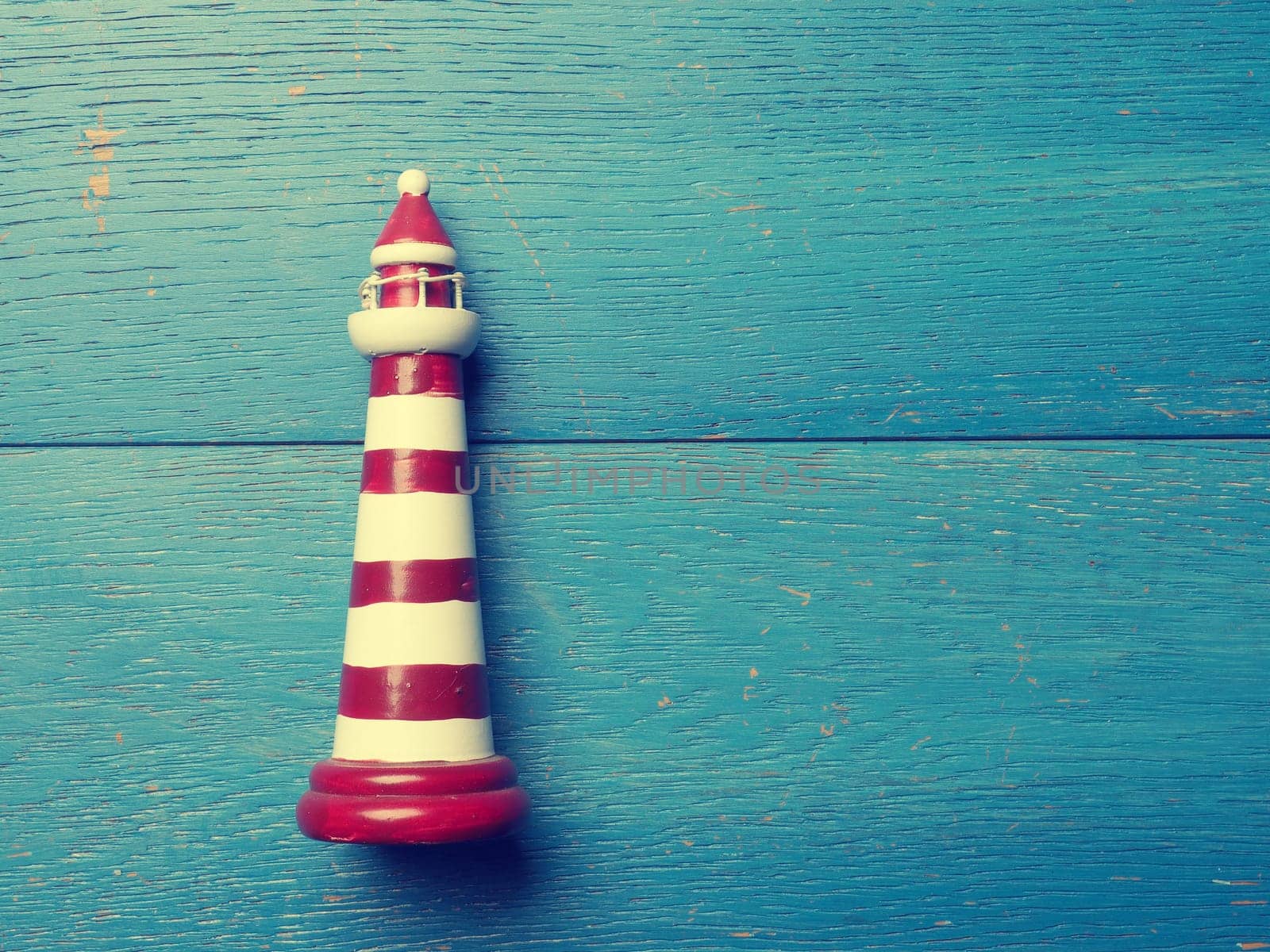 Small lighthouse on a rustic wooden background using as vacation card