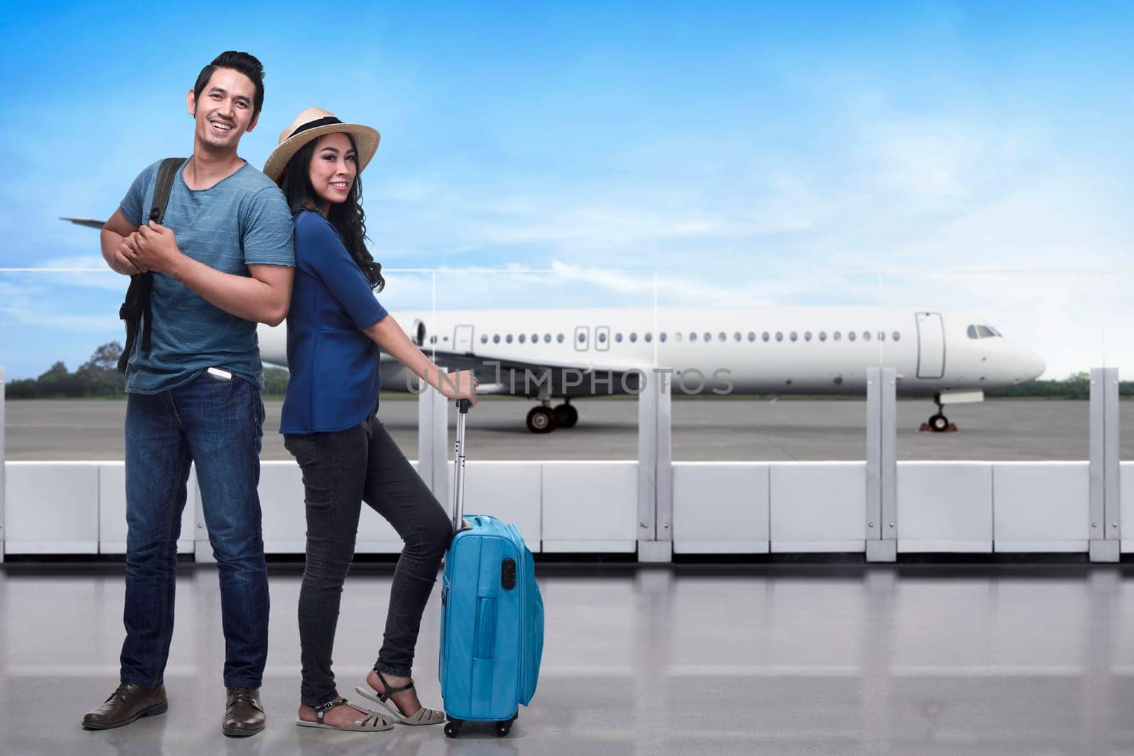 Portrait of asian tourist couple with backpack and suitcase standing against airplane background