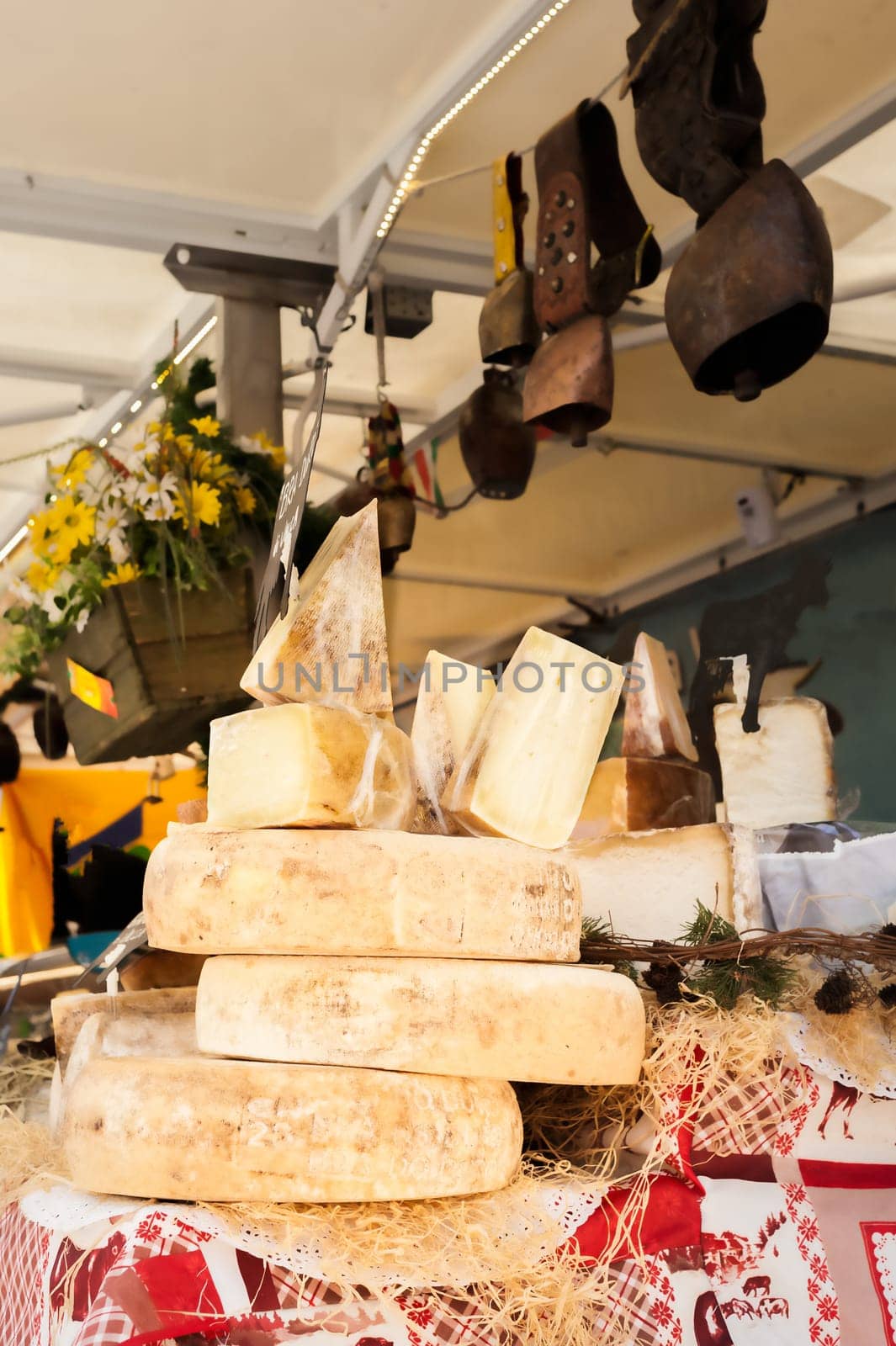 Cheeses and cut pieces in bulk on the counter of a market. This cheese is Montasio and is typical of Italy.