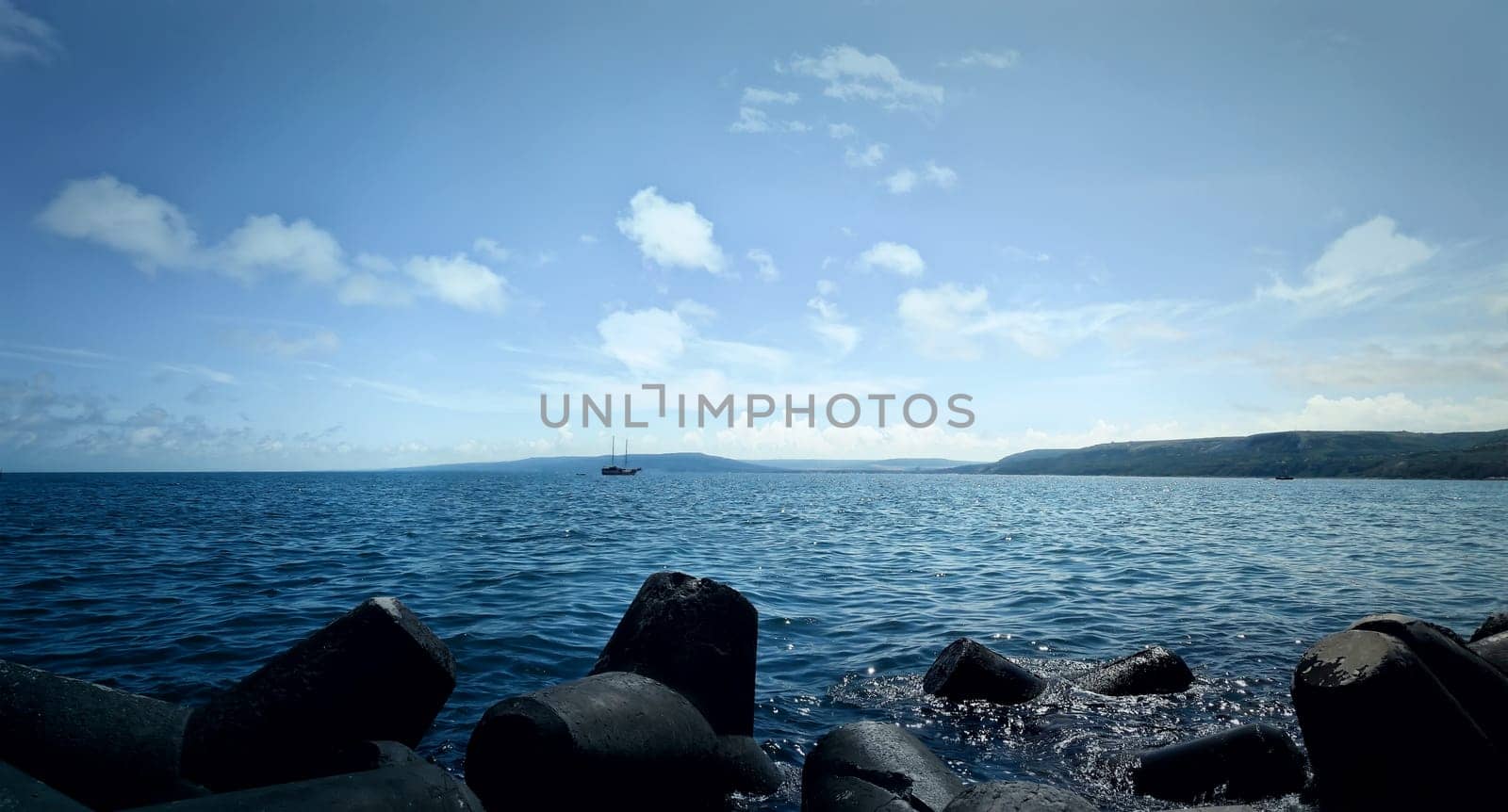 Colorful panoramic view of the coast of Black Sea with a ship floating near the harbor at Balchik city, Bulgaria. Summer holiday screensaver. Joy, happiness and recreation concept