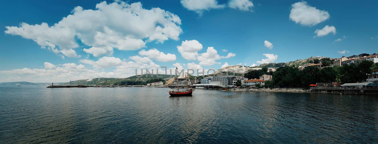 Clear morning panoramic view with a sail boat floating in the Black Sea, Balchik city, Bulgaria. Summer vacation background. Joy, happiness and recreation concept