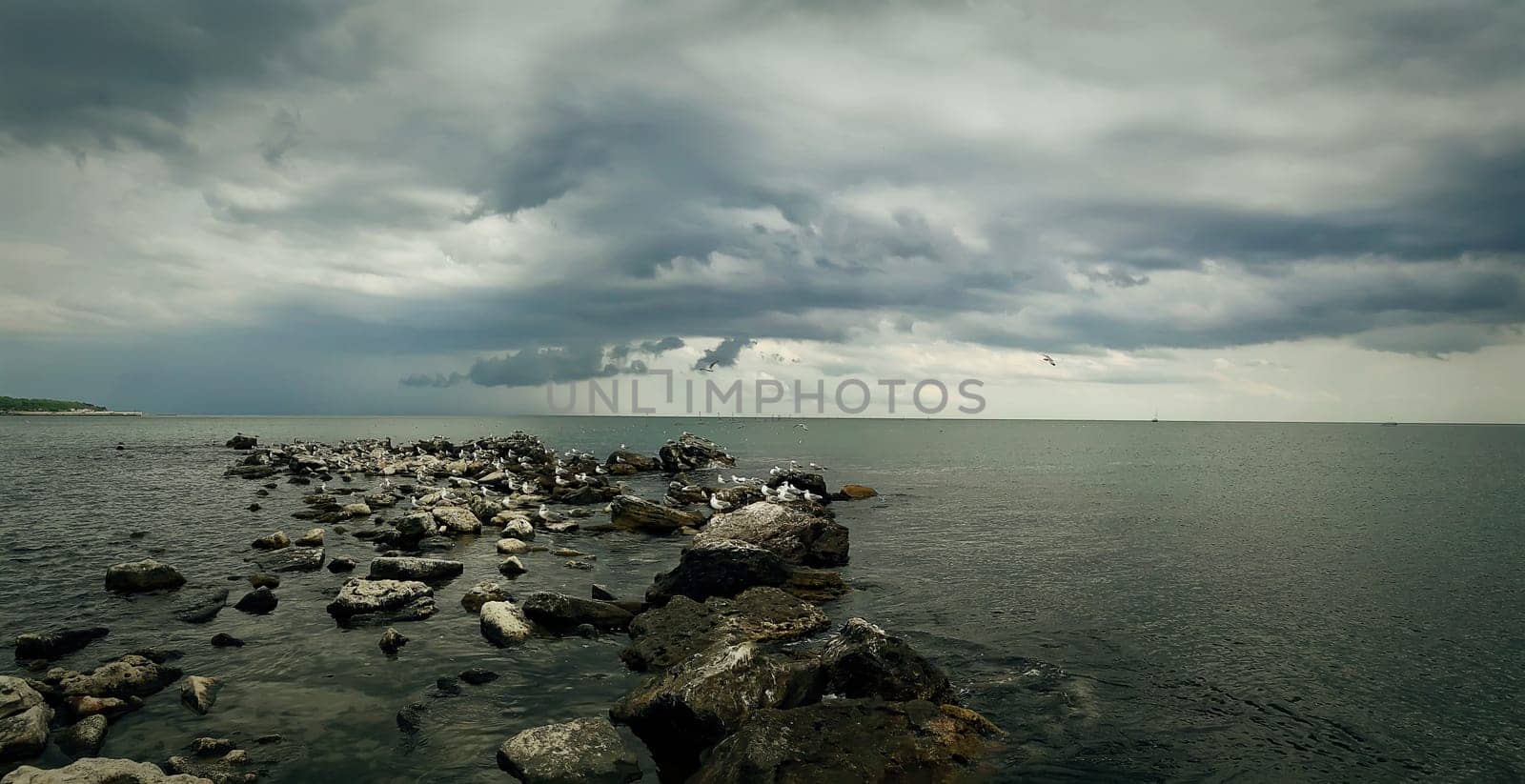 Seascape of stone beach with a dramatic cloudy sky. Beautiful view at the coast of the Black Sea in Balchik city, Bulgaria.