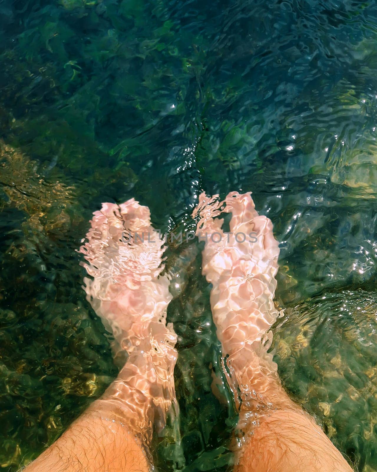 Close up of male legs in the clear sea water. Summer vacation, resting and recreation concept