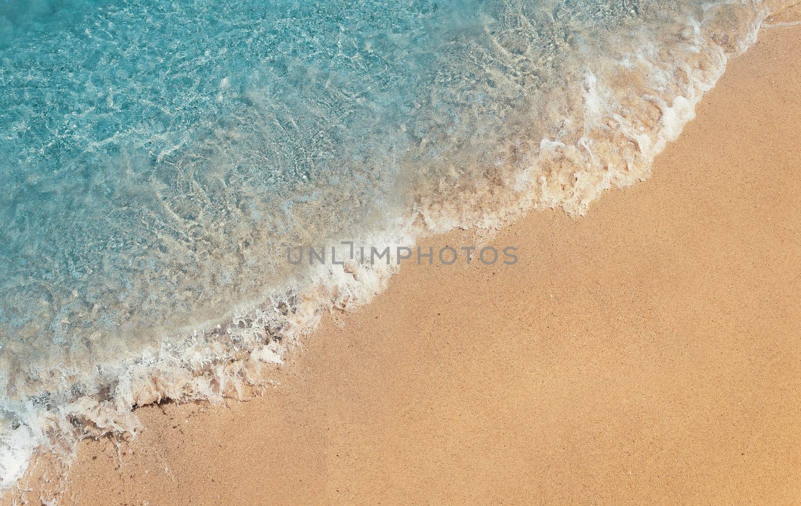 Soft foaming wave of blue sea on a sand beach. Summer vacation background, holiday recreation concept