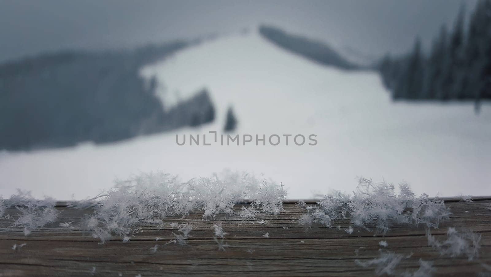 Wooden table covered with soft snowflakes on a beutiful mountains background