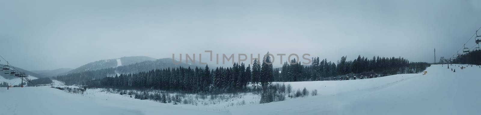 Panoramic view over the Carpathian mountains in Ukraine.Gondola lift on ski resort at windy winter day and snow covered fir trees.