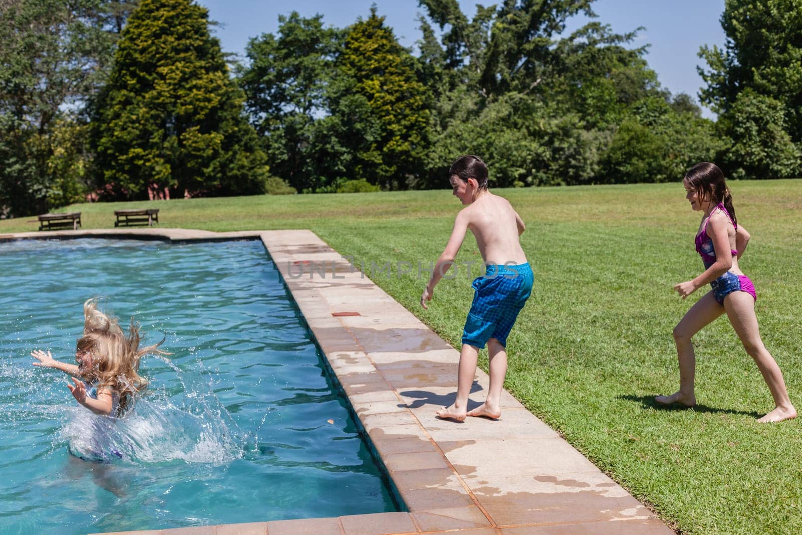 Girls boy running jumping into home  swimming pool summer playtime