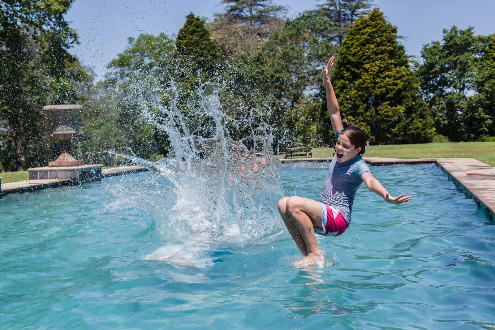 Girls running jumping into home  swimming pool summer playtime