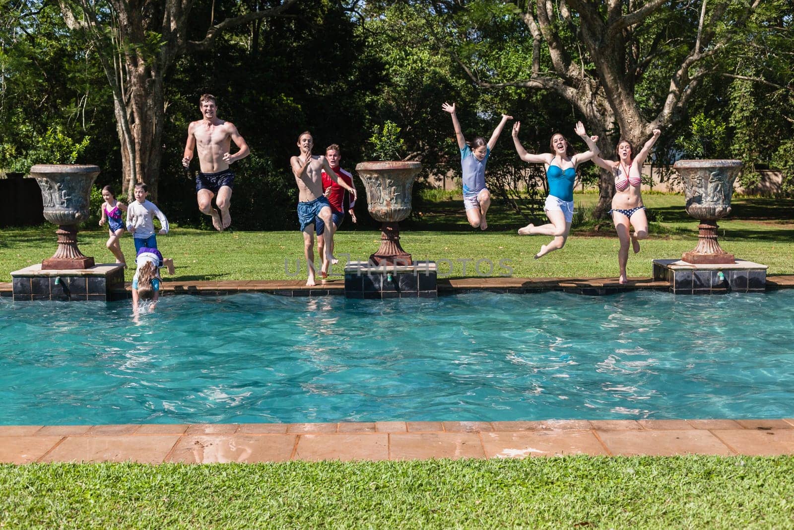 Girls boys teenagers young running jumping into home  swimming pool summer playtime