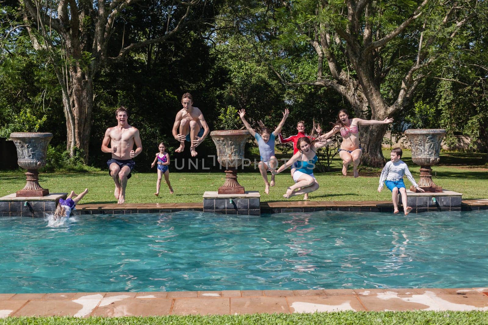 Girls boys teenagers young running jumping into home  swimming pool summer playtime