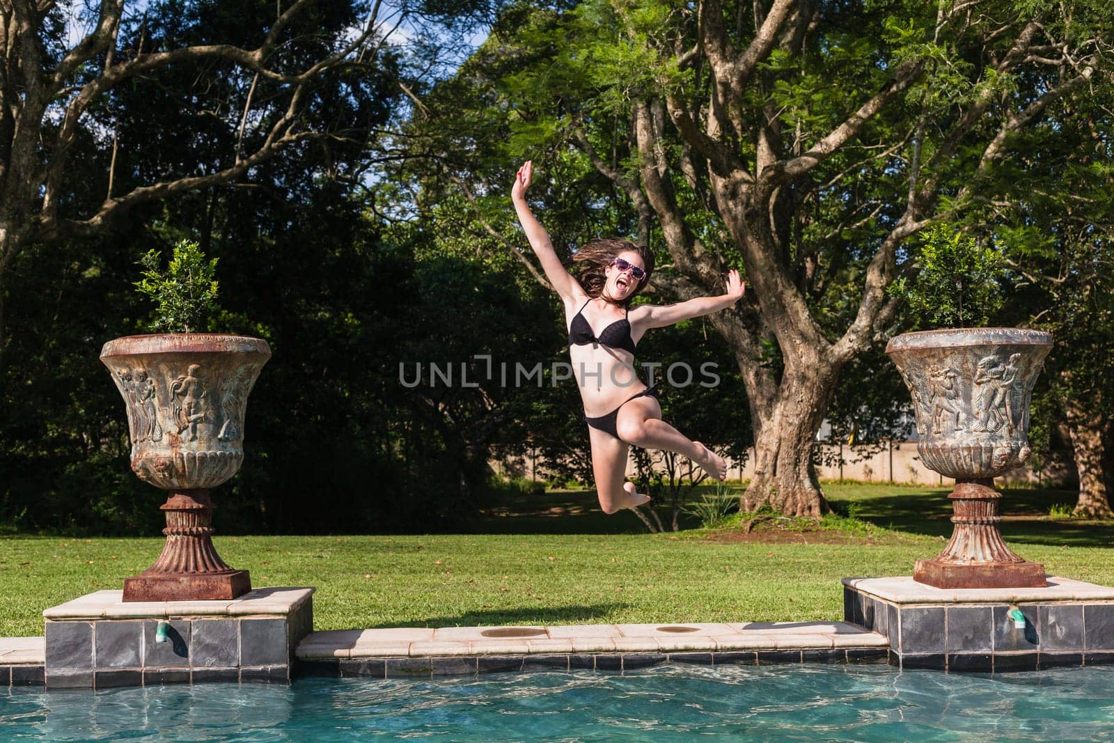 Girl running jumping into home swimming pool summer playtime