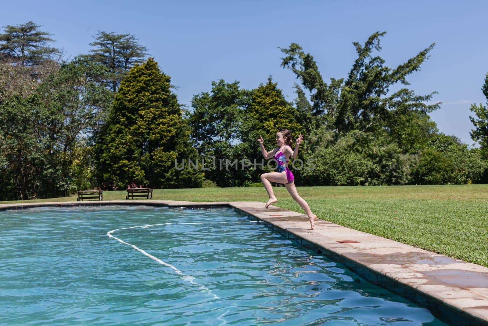 Girl running jumping into home swimming pool summer playtime