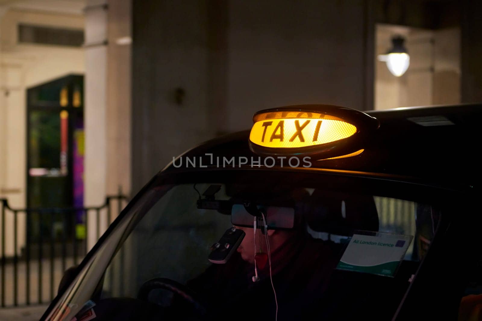Low key detail of London black cab sign turned on at night.