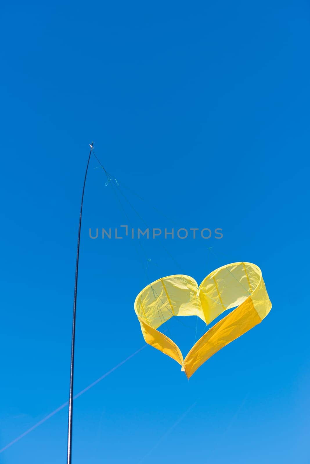 yellow heart shaped kite against a blue sky