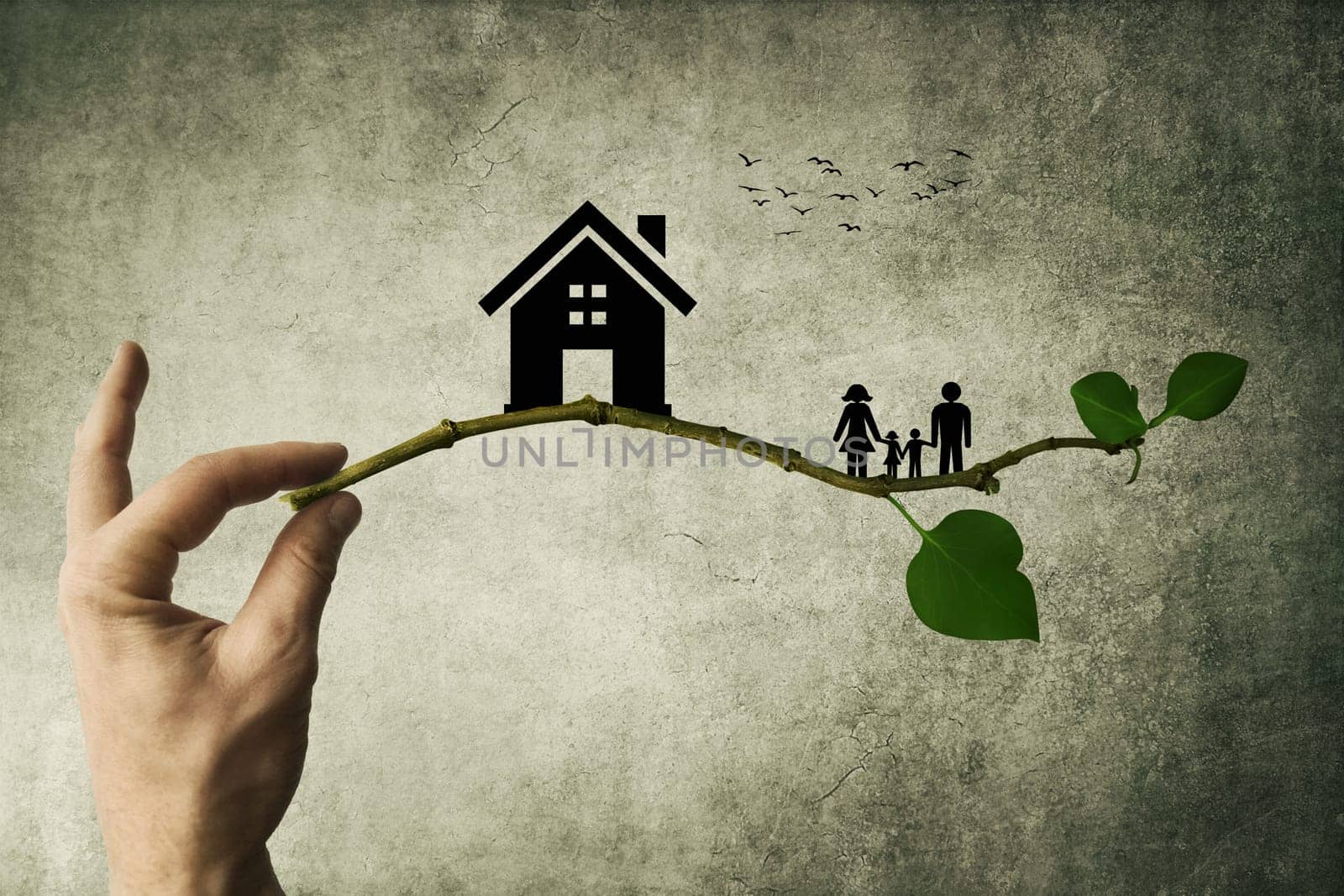 Human hand holding a tree branch with silhouettes of house and family. The concept of a happy family. Eco life