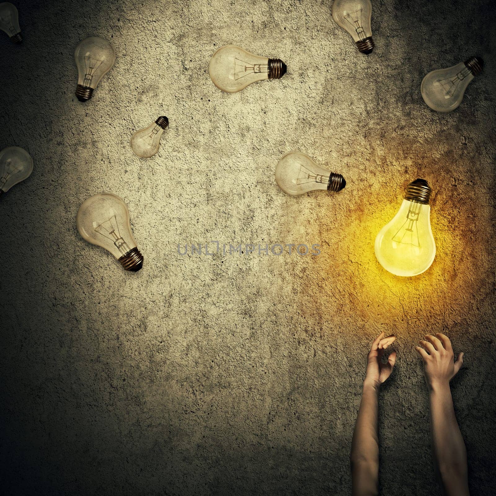 Abstract idea concept as human hands stretched out and juggling with a lot of lightbulbs, one of them glowing. Good idea concept, wealth and success. Inspiration and imagination.