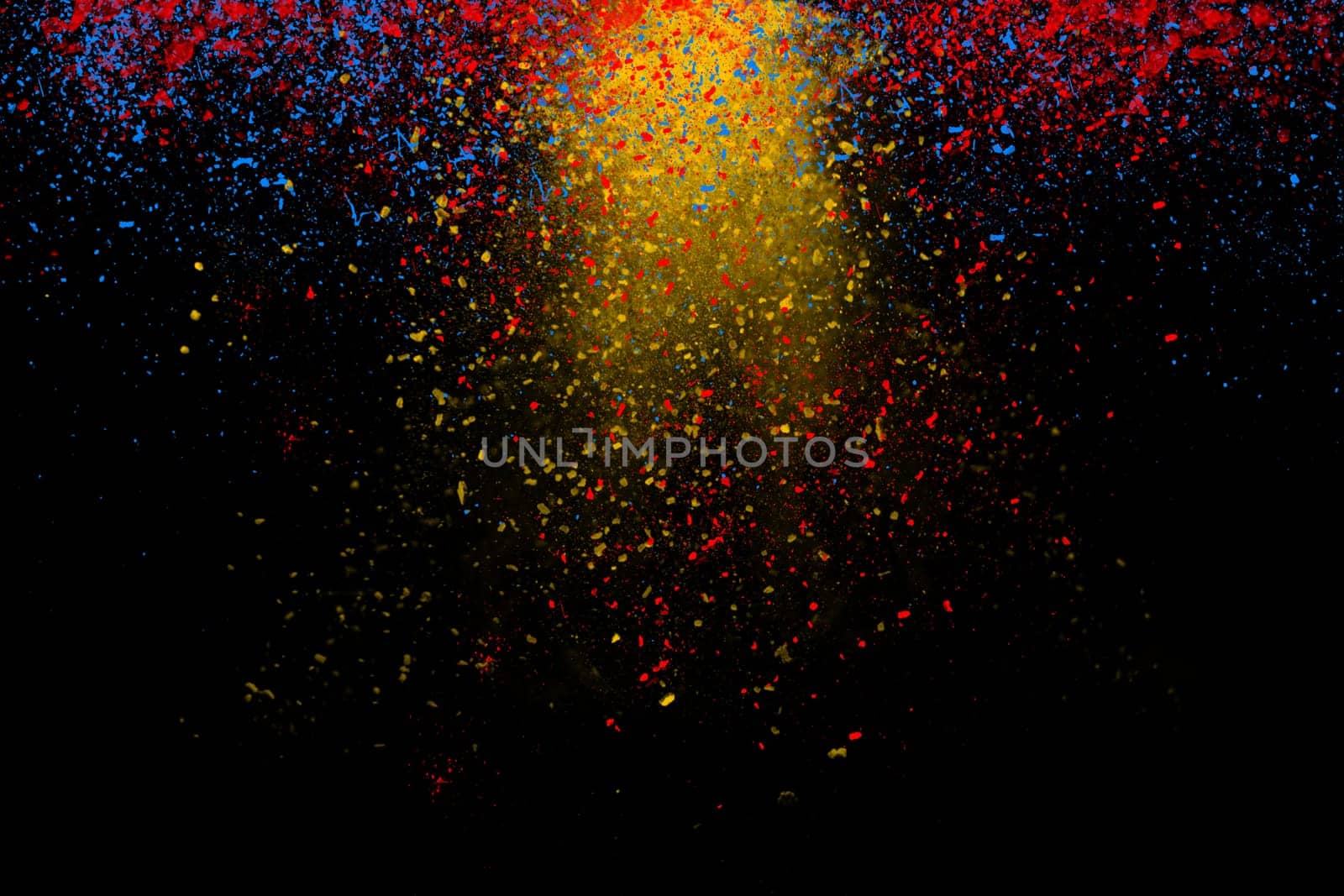 Freeze motion of colorful powder coming down isolated on dark black background. Abstract design of falling yellow, blue and red dust. Particles cloud wallpaper.