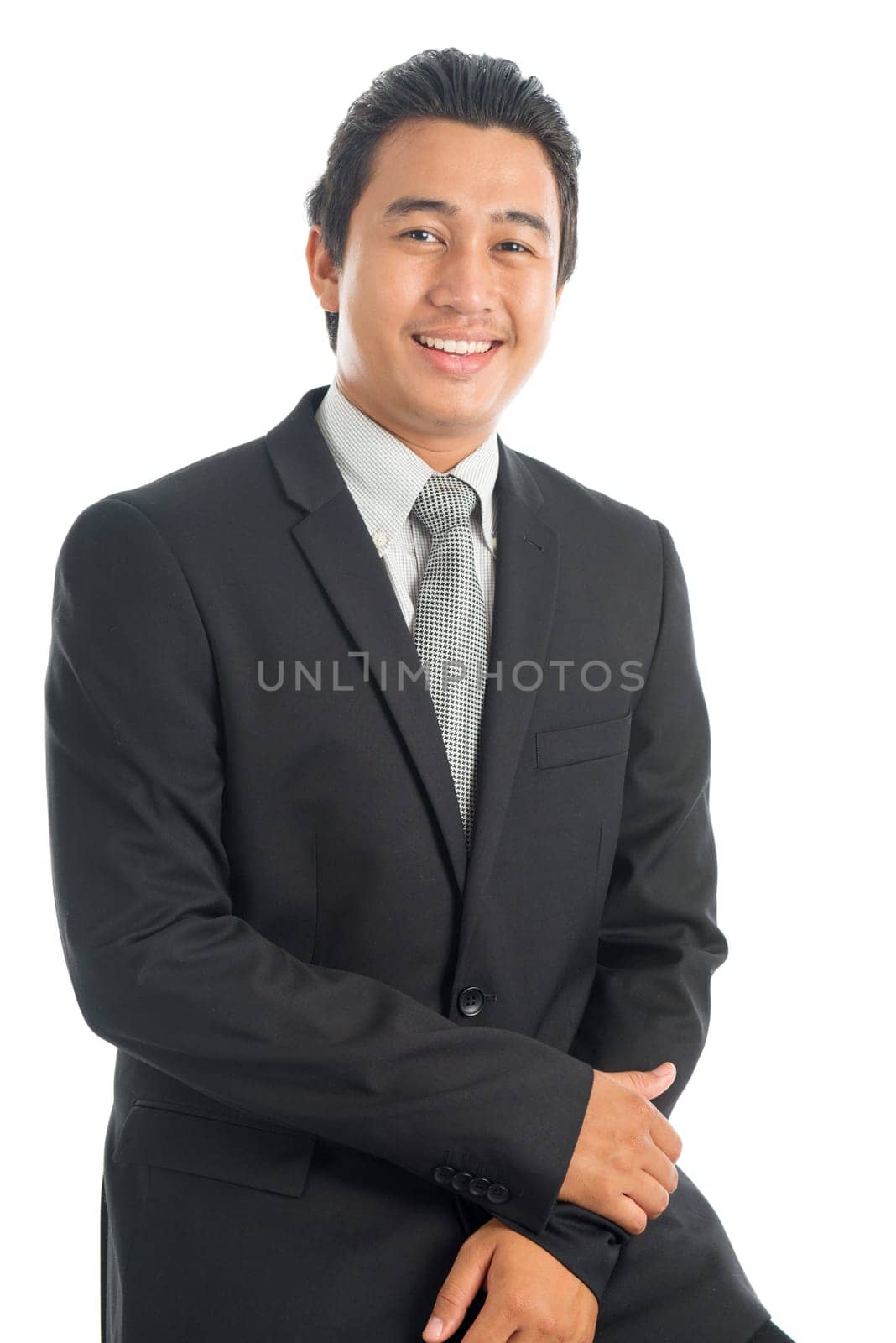 Portrait of happy young Southeast Asian businessman sitting on chair, isolated on white background.
