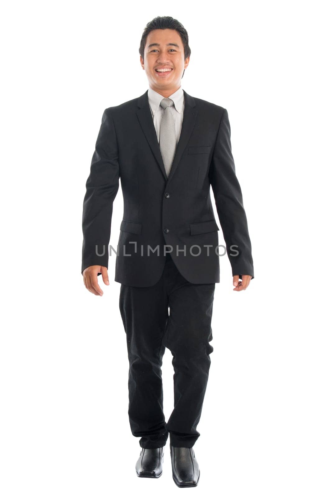 Full body front view portrait of good looking young Southeast Asian businessman walking, isolated on white background.