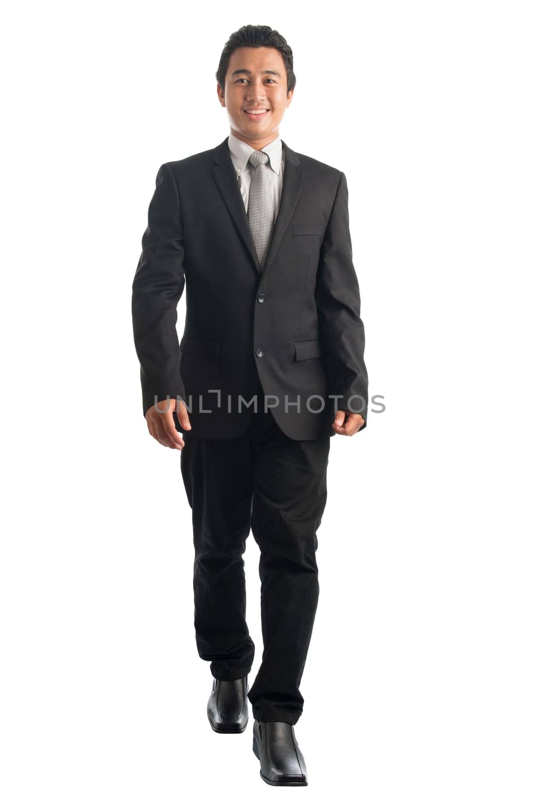 Full body front view portrait of handsome young Southeast Asian businessman walking, isolated on white background.