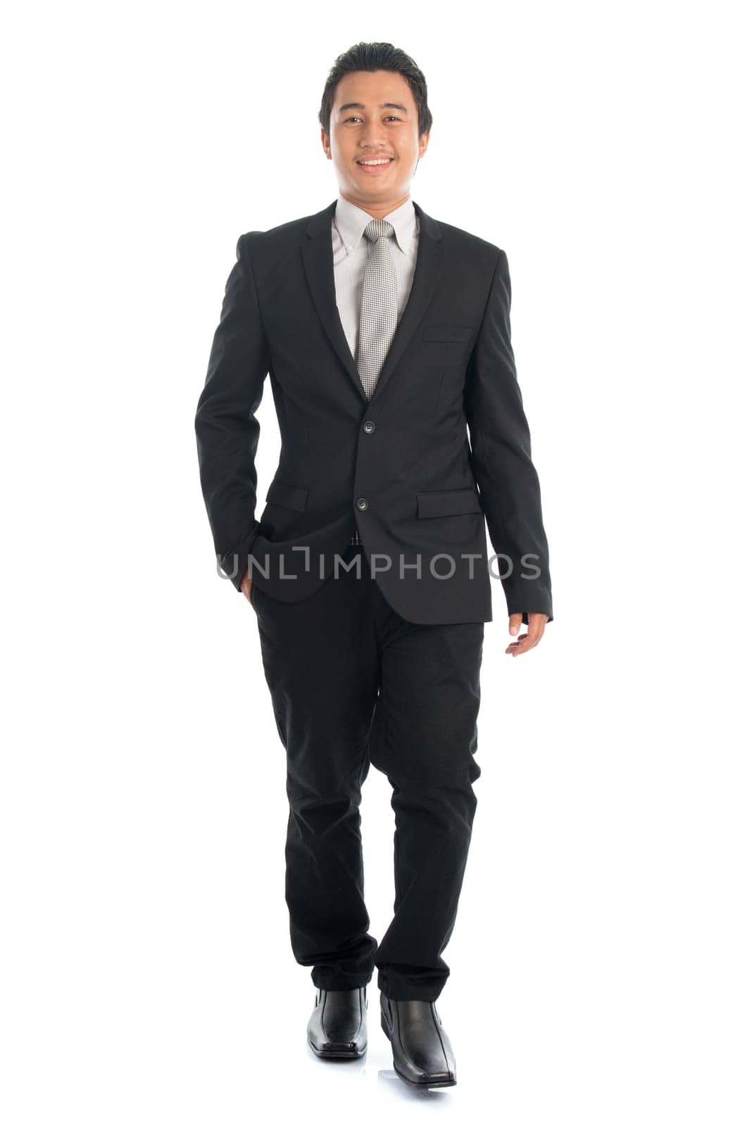 Full length front view portrait of attractive young Southeast Asian businessman walking, isolated on white background.