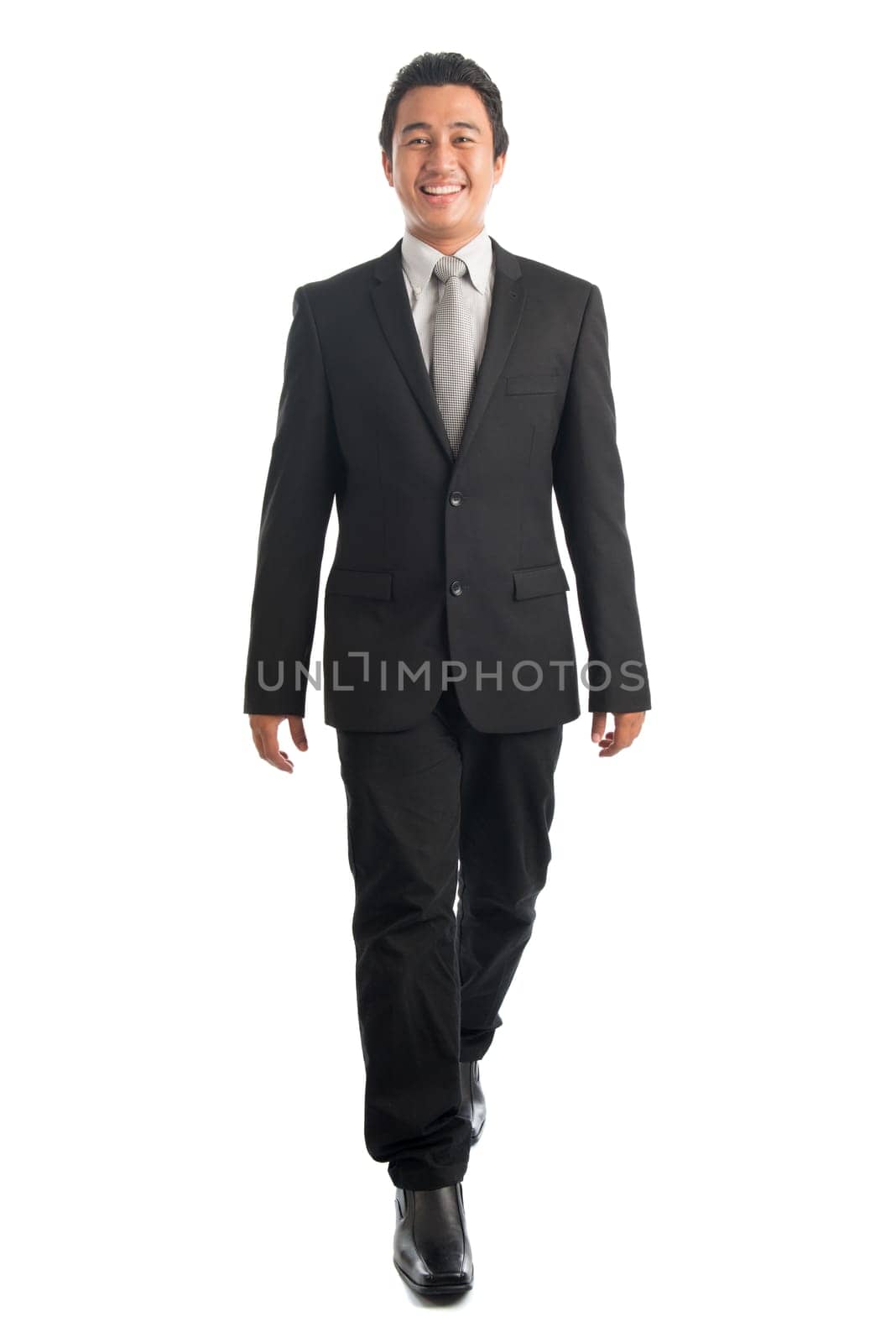 Full body front view portrait of smart young Southeast Asian businessman walking, isolated on white background.