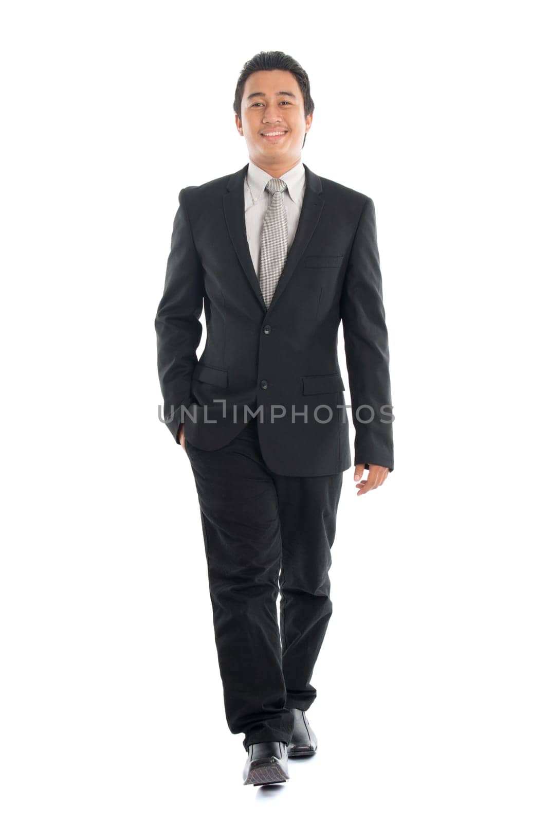 Full body front view portrait of young Southeast Asian businessman walking, isolated on white background.