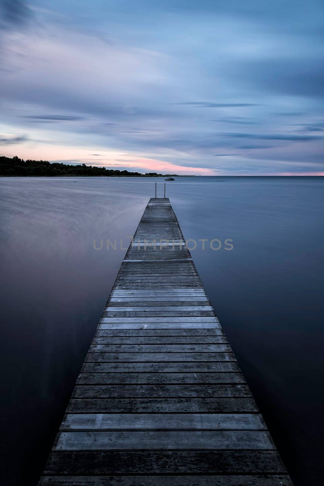 Pier into the Ocean at sunset with clouds.
