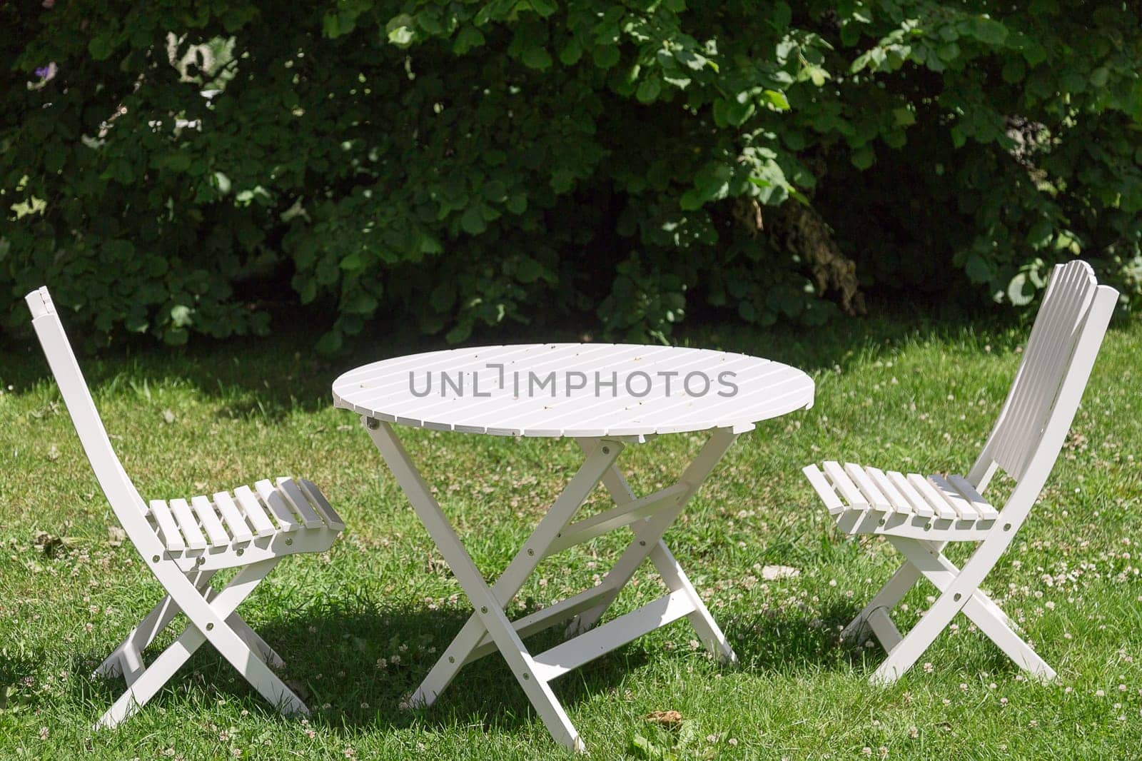 White Garden Chairs and Table with green grass.