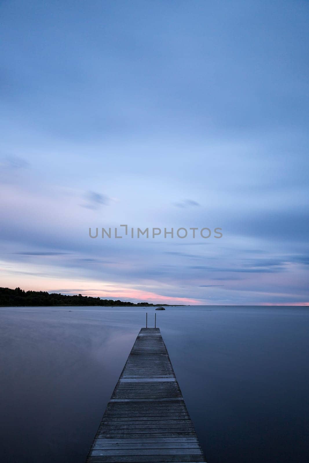 Pier into the Ocean at sunset with clouds.