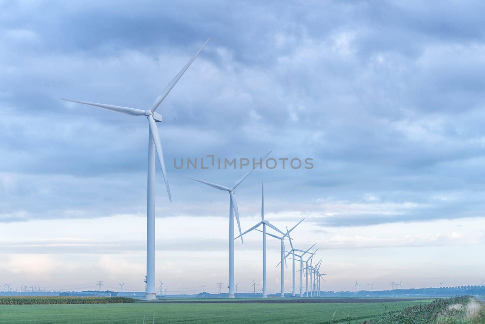 row of wind turbines in early morning in a flat dutch landscape