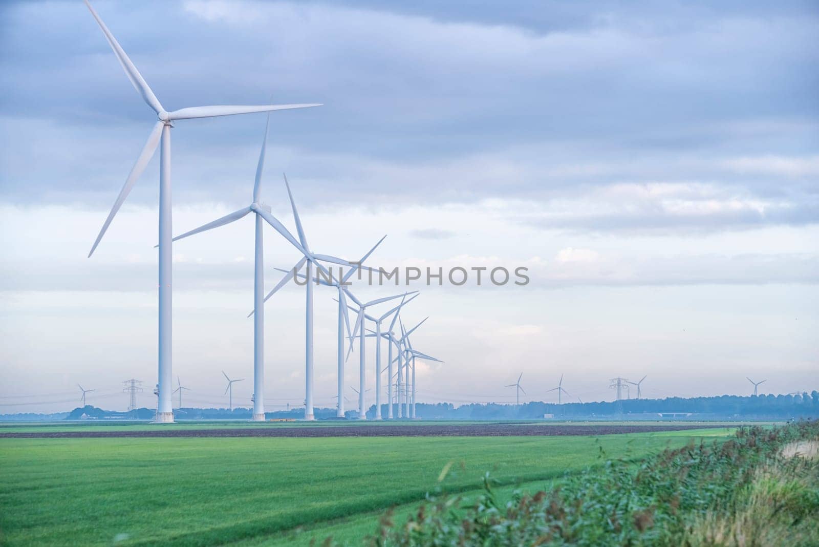 row of wind turbines in early morning in a flat dutch landscape