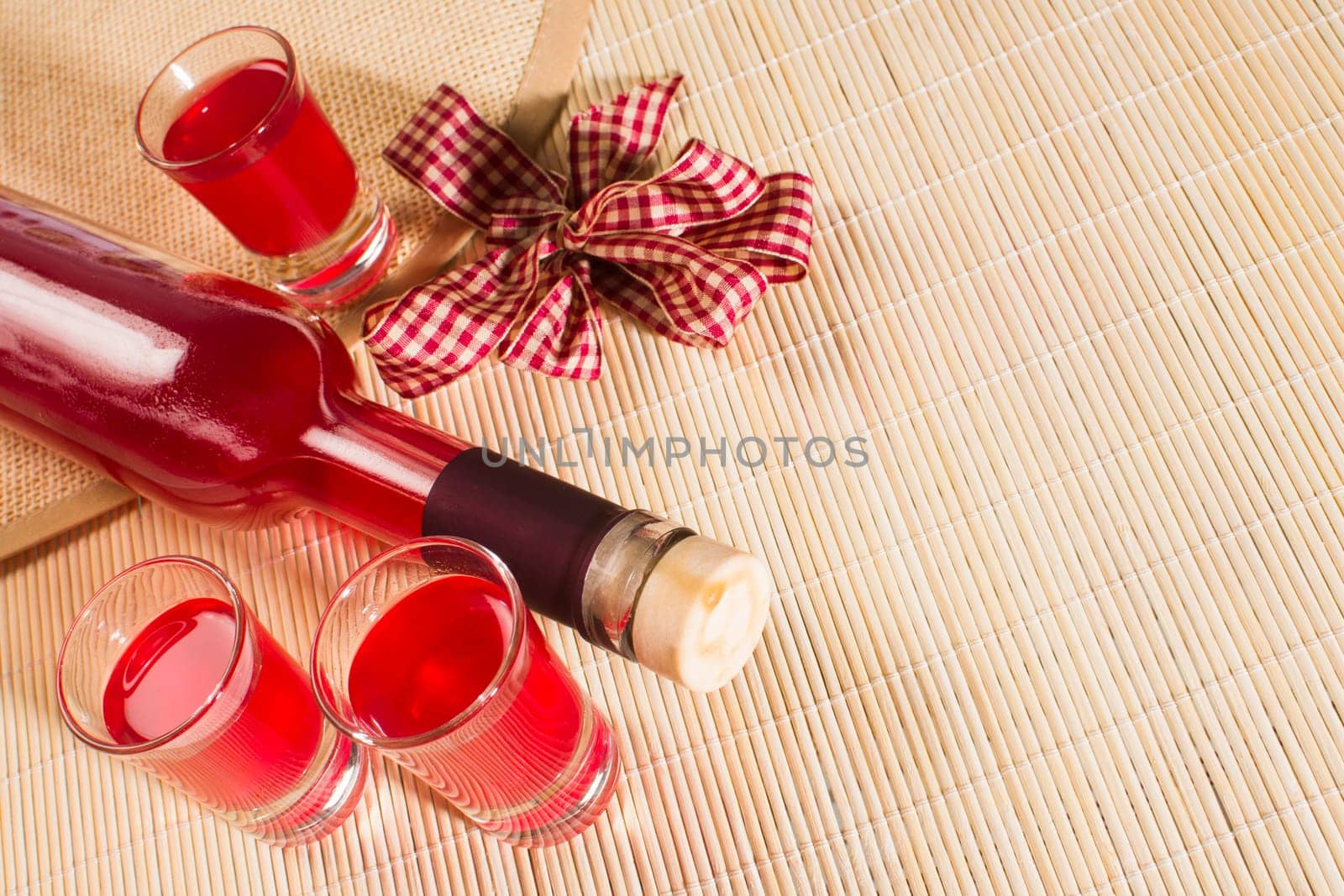 Still life with red alcoholic drink in bottle and glasses on natural background.