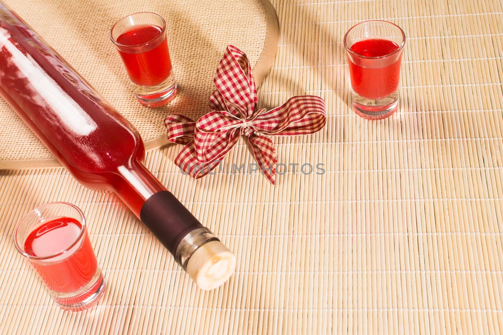 Bottle and glasses for alcohol are on natural background.
