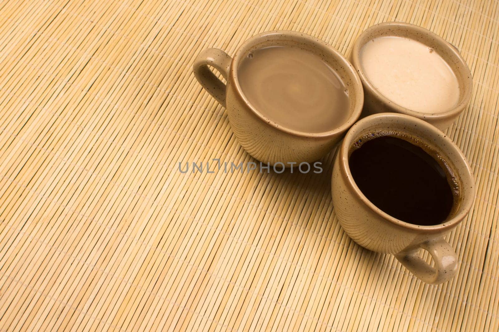 Three cups of different coffee are on natural background.