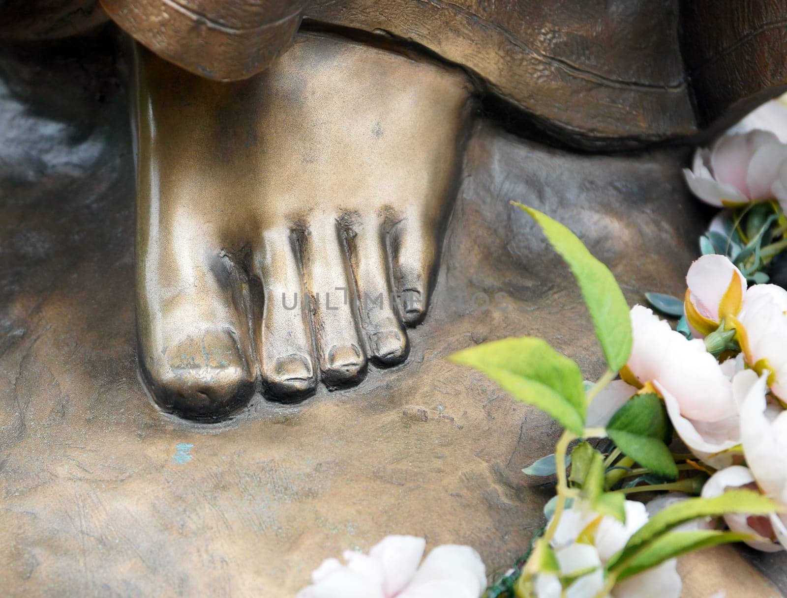 Foot of bronze statue with flowers
