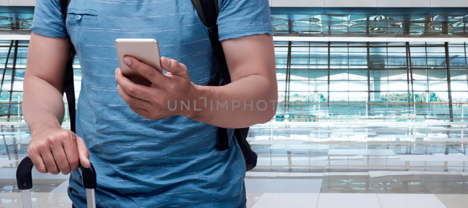 Traveler asian man with suitcase holding mobile phone in the airport terminal