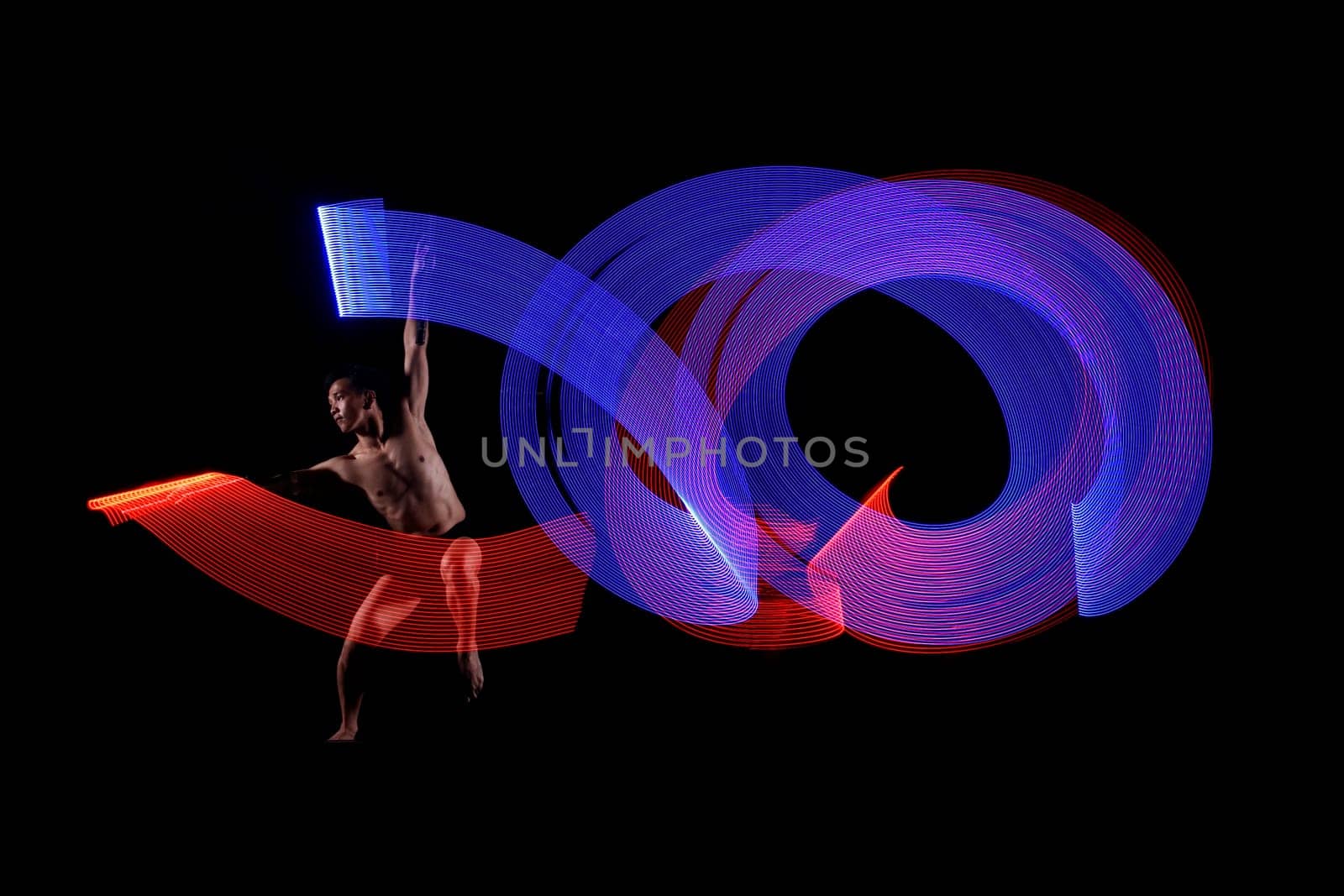 Young man ballet dancing with blue and red lights effect agaisnt black background