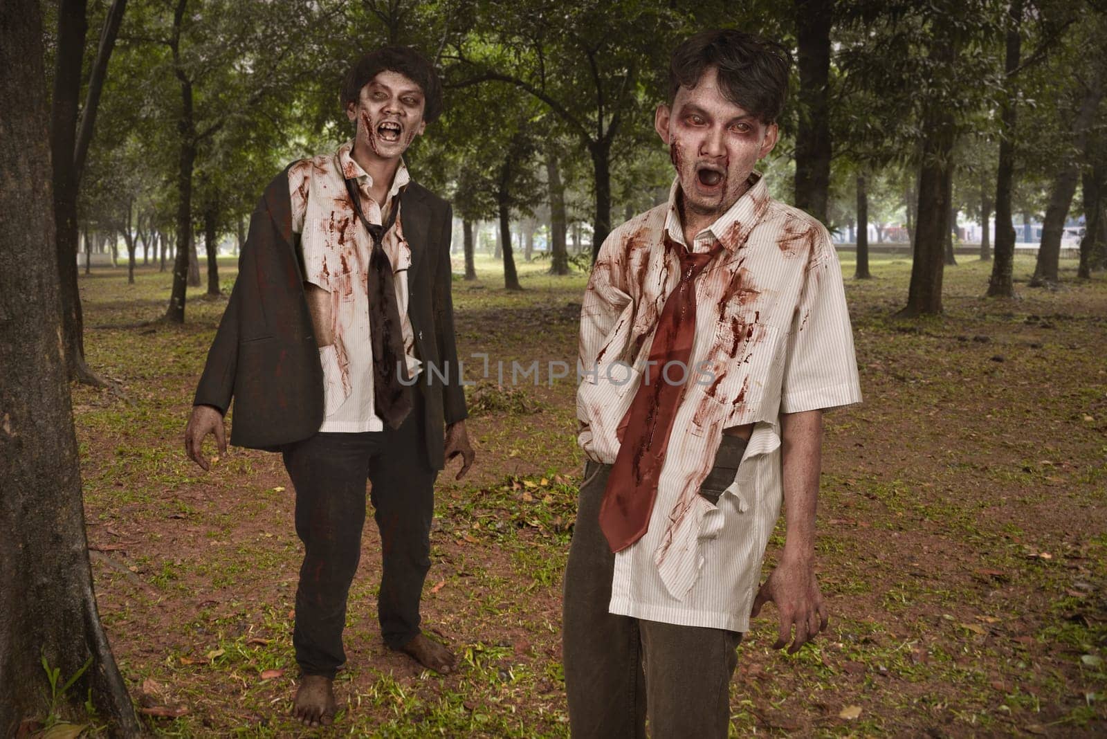 Two creepy and bloody asian zombies in clothes on the woods