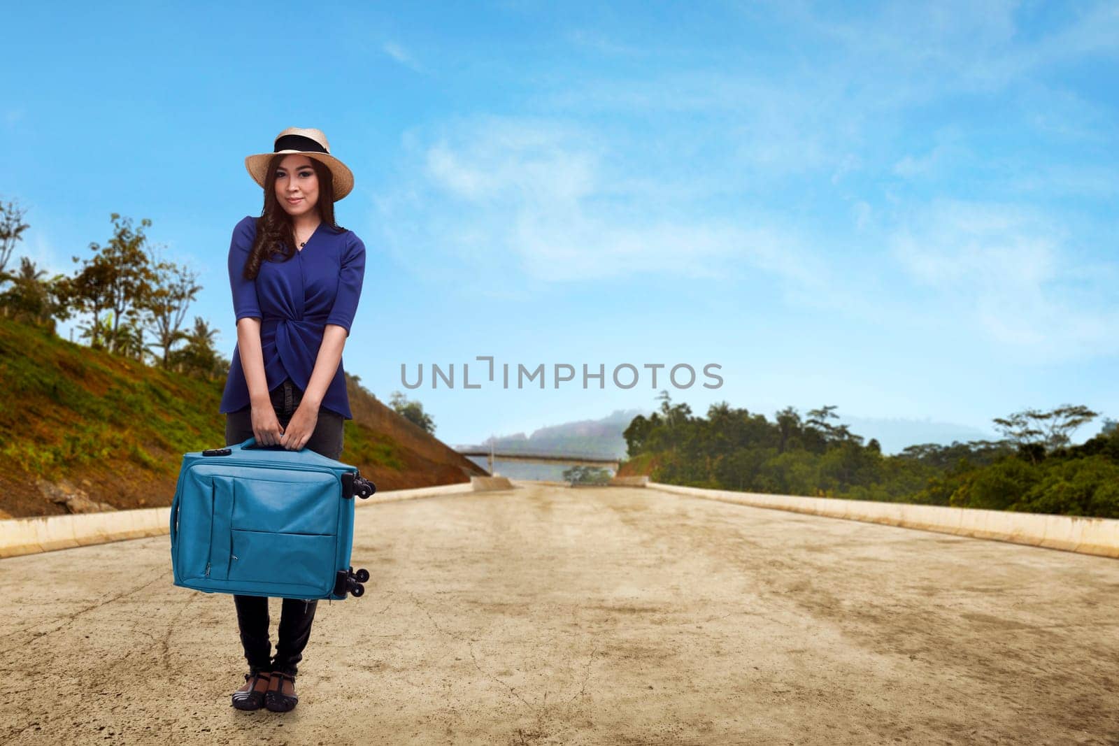 Pretty asian traveler with hat holding suitcase on the street